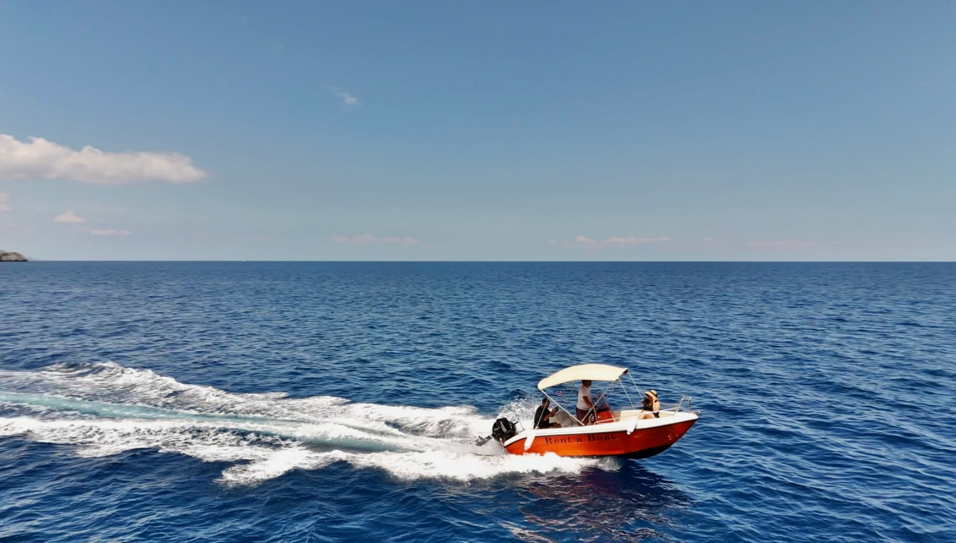 Orange and white RÉMA rental boat cruising across the open Mediterranean sea