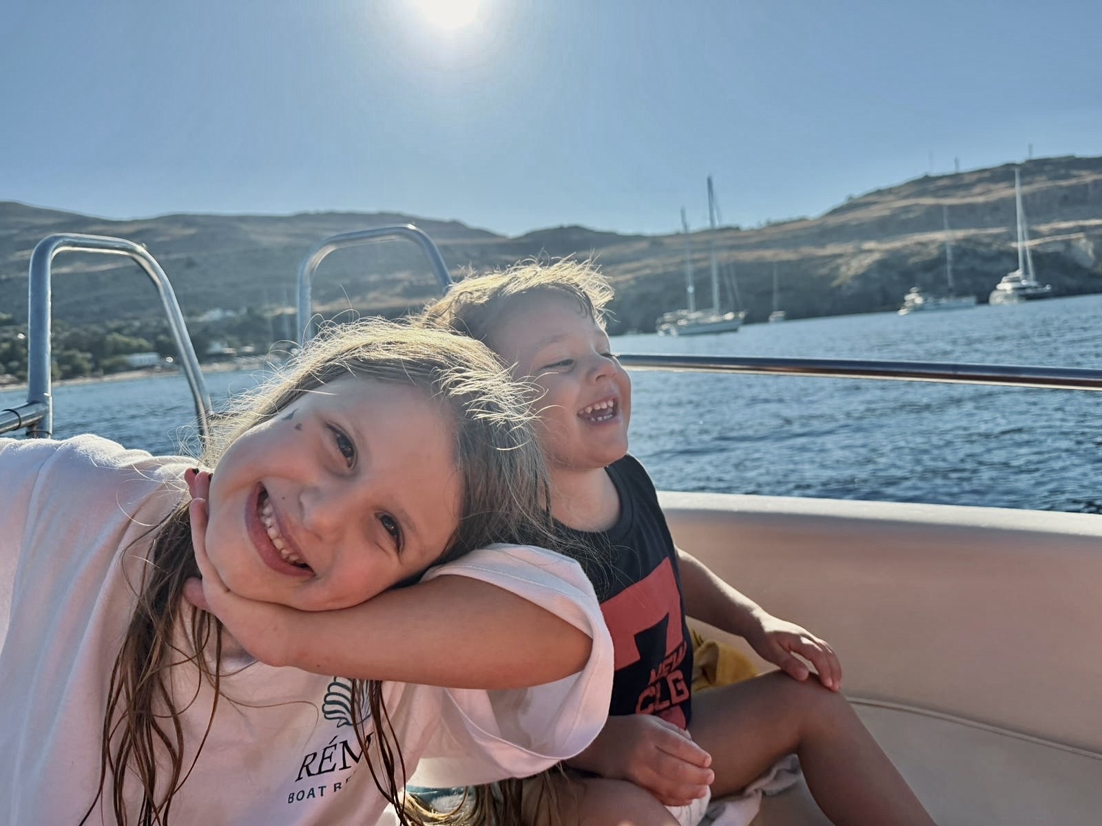 Two children smiling and laughing together on a RÉMA boat on a sunny day at sea